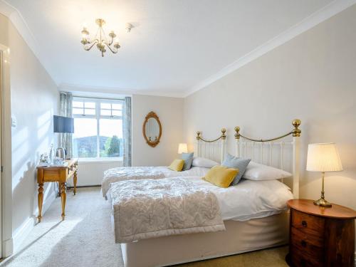 a white bedroom with a bed and a window at The Bield in Aberfoyle