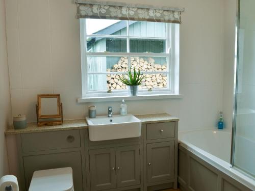 baño con lavabo y ventana en Havannah Cottage en Alnham