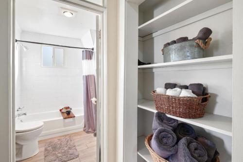 a bathroom with a toilet and towels on shelves at Spacious City House in Colorado Springs