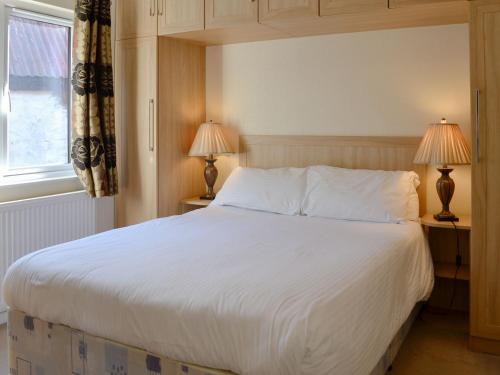 a bedroom with a large white bed with two lamps at Lodge E- Uk33091 in Dinnet