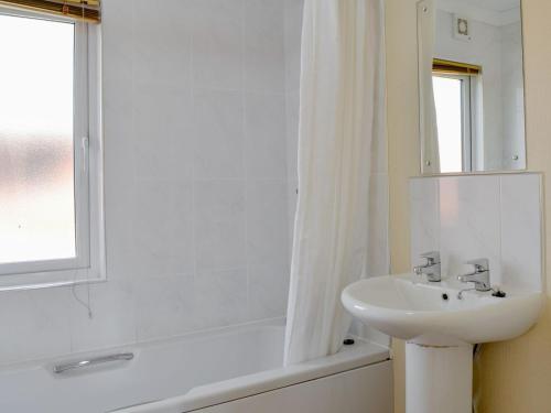 a white bathroom with a sink and a bath tub at Lodge E- Uk33091 in Dinnet