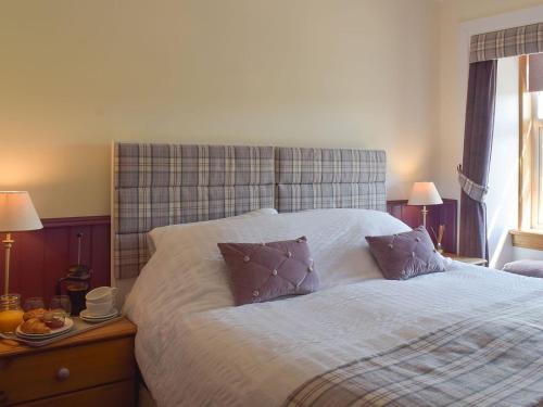a bedroom with a large bed with two pillows at Thistle Cottage in Mauchline
