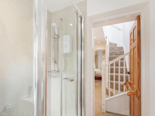 a bathroom with a walk in shower next to a staircase at Quince Cottage in Flookburgh