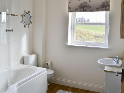 a bathroom with a tub and a toilet and a window at Castle Holt in Otterburn