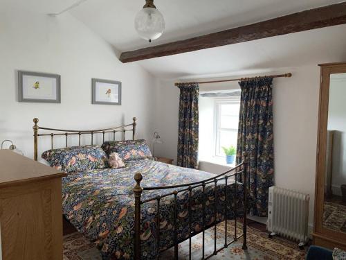 a bedroom with a bed and a window at Penny Black Cottage in Ingleton