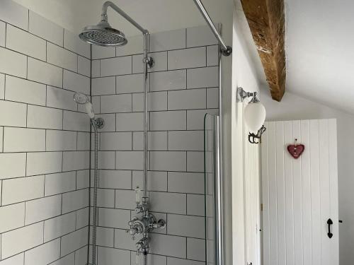 a bathroom with a shower with white tiled walls at Penny Black Cottage in Ingleton