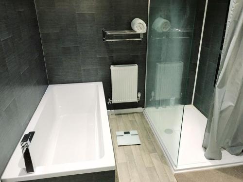 a bathroom with a white tub and a shower at Deany Apartment in Bridlington