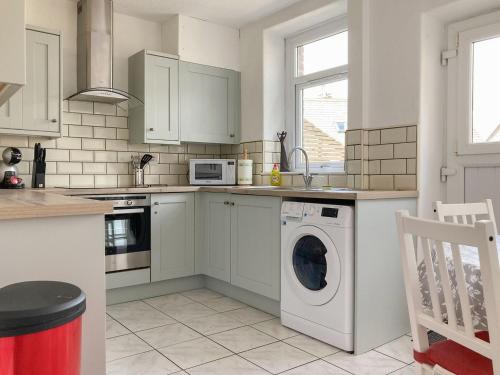 a white kitchen with a washer and dryer in it at Holmfield in Buxton