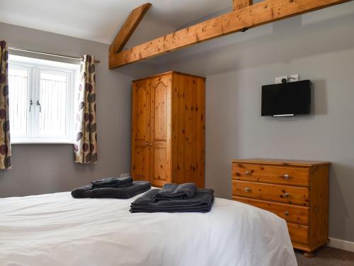 a bedroom with a bed with a dresser and a tv at Owl Cottage in Ryton