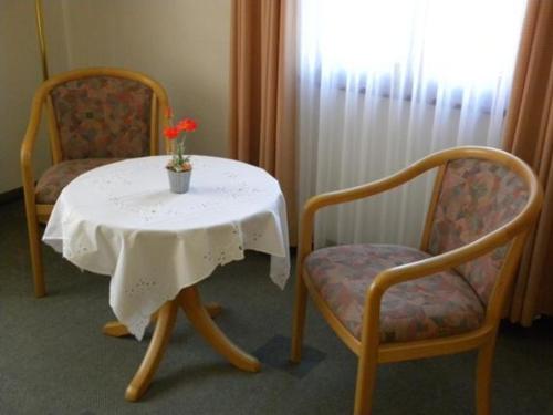 a table and two chairs with a vase with a flower on it at Hotel Restaurant Adler Bühlertal in Bühlertal