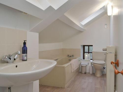 a bathroom with a sink and a tub and a toilet at Smithy House in Bampton