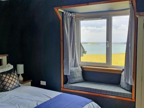 a bedroom with a window with a view of the ocean at Tor Aluinn in Skullomie