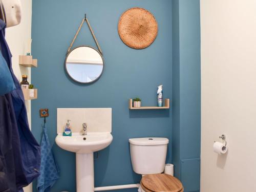 a blue bathroom with a toilet and a sink at Crown Cottage in Danehill
