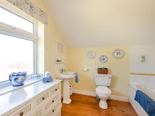 a bathroom with a toilet and a sink and a window at Edlington Hall Cottage in Edlington