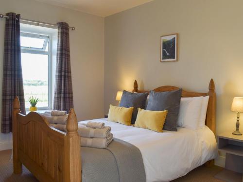 een slaapkamer met een groot bed met kussens en een raam bij West Cottage in Fife