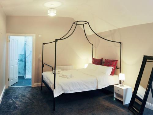 a bedroom with a canopy bed with white sheets and red pillows at Machermore Castle in Newton Stewart