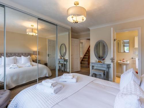 a bedroom with two beds and a mirror at The Reeds in Wroxham