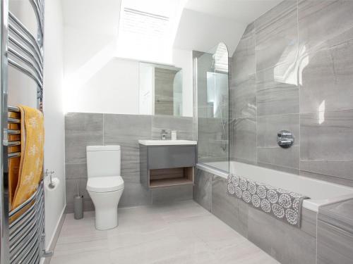 a bathroom with a toilet and a sink and a tub at The Old School House in North Tawton