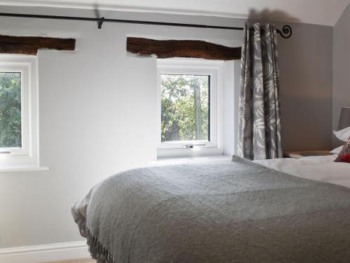 a bedroom with a bed and two windows at Treacle Cottage - Uk12912 in Warton