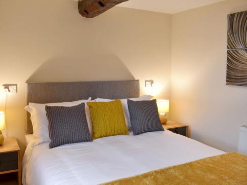 sypialnia z białym łóżkiem z żółtymi i niebieskimi poduszkami w obiekcie The Mews w mieście Appleby