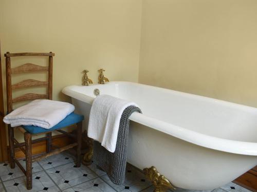 a white bath tub in a bathroom with a chair at 4 The Green in Richmond