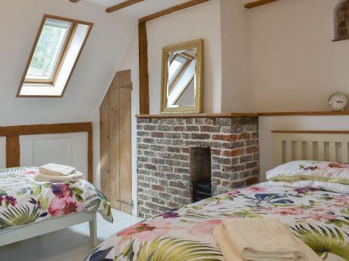a bedroom with a bed and a brick fireplace at Holme Cottage in Eastry