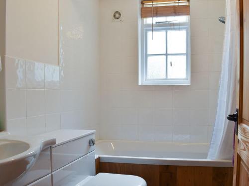 a bathroom with a tub and a sink and a toilet at Holme Cottage in Eastry
