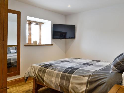 a bedroom with a bed and a flat screen tv at The Byres Methera in St Bees