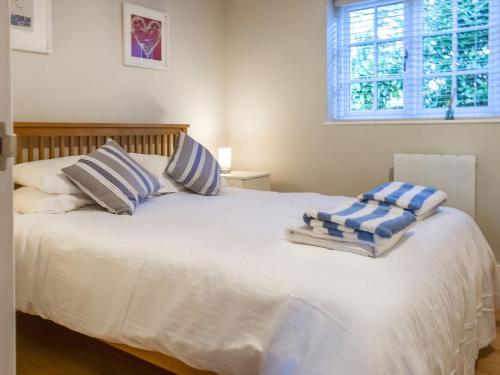 a bedroom with a white bed with blue and white pillows at Camelia Cottage-uk37205 in Sancreed