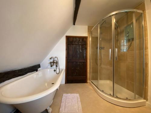 a bathroom with a tub and a glass shower at Dairy Farm in Sherfield English