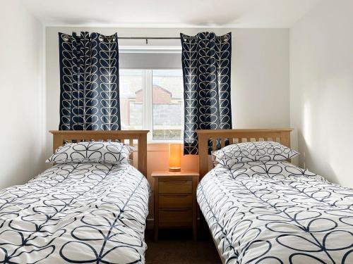 two twin beds in a room with a window at Academy Street Cottage in Tain