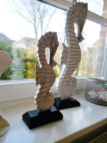 a pair of wooden sculptures sitting on a shelf next to a window at Hotel Garni Friesenhuus in Greetsiel