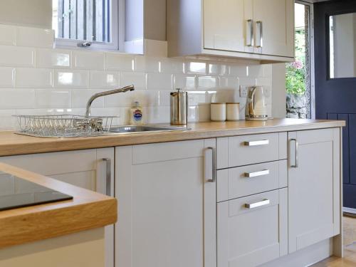 a kitchen with white cabinets and a sink at Threagill Cottage - Uk12913 in Warton