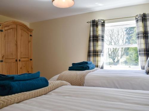 a bedroom with two beds and a window at Span Carr Cottage in Ashover