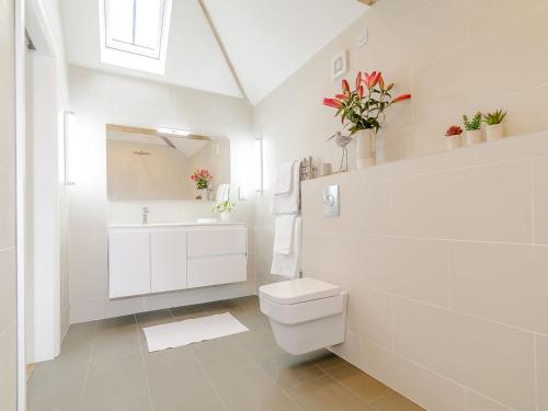 a white bathroom with a toilet and a sink at The Dairy in Elsham