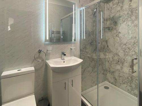 Brigham的住宿－The Oak Apartment，白色的浴室设有水槽和淋浴。