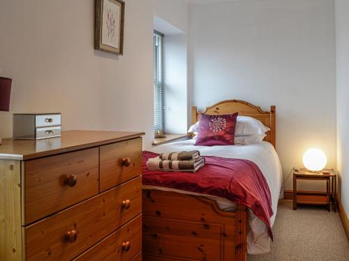a bedroom with a bed with a wooden dresser and a drawer at Carse View Cottage in Abernethy