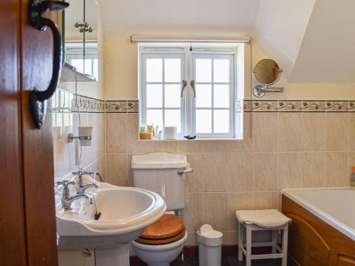 a bathroom with a sink and a toilet and a window at Myrtle Cottage in Puncknowle