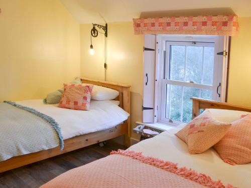 a bedroom with two beds and a window at Lake View Cottage in Falstone