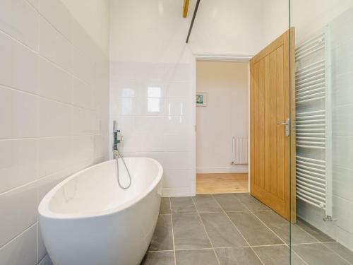 a white bathroom with a tub and a glass door at Abigails Cottage in Trimdon Grange