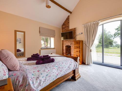 a bedroom with a bed with purple pillows on it at The Coach House - Uk32461 in Burlton
