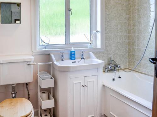 a bathroom with a sink and a tub and a window at Woodend Farmhouse Halmyre in Haugh of Urr
