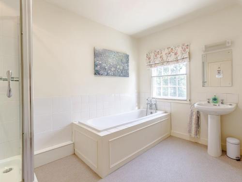 Baño blanco con bañera y lavamanos en Pattiswick Hall en Stisted