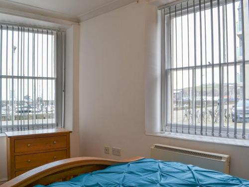 a bedroom with a bed and two windows at Duncan Square in Whitehaven