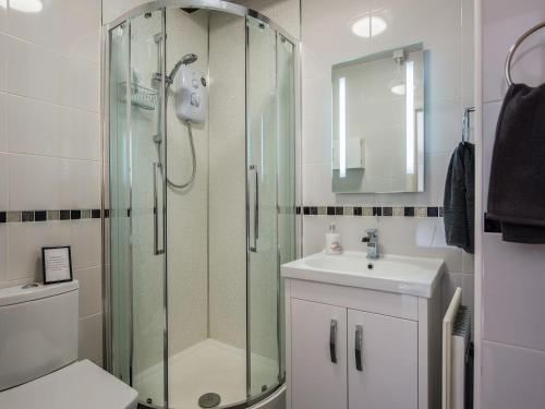 a bathroom with a glass shower and a sink at The Coach House in Marrick