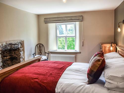 a bedroom with a bed with a red blanket at Conn Cottage in Bampton