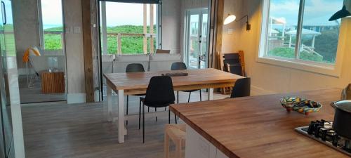 - une cuisine avec une table en bois, des chaises et des fenêtres dans l'établissement Rooster Beach - Hope Town, Elbow Cay, à Lubbers Quarters Cay