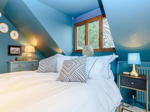 a blue bedroom with a white bed and a window at River Test View in Chilbolton