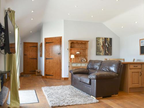 a living room with a leather couch and a table at The Barn in Baltonsborough