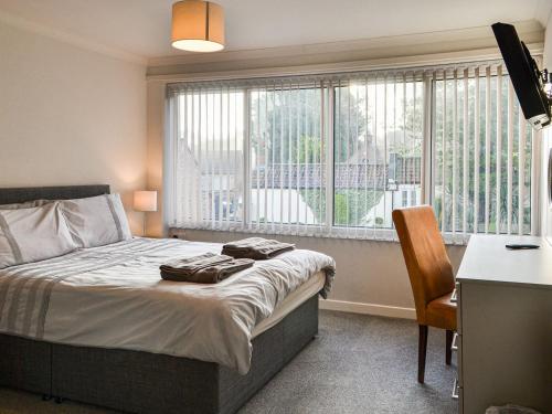 a bedroom with a bed and a desk and a window at Cheviot in Walkington